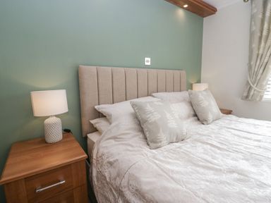 A bedroom with a bed with patterned cushions and matching curtains and bedside tables with lamps at Swifts Reach Lodge Kirkstone 10 Limefitt Park near Windermere