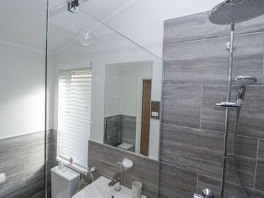 A bathroom with a shower, sink, toilet, mirror, and window blinds at Swifts Reach Lodge Kirkstone 10 Limefitt Park near Windermere