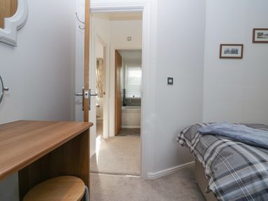 A bedroom with a bed, bedside table, wall mirror, and an open door leading to a hallway and bathroom at Swifts Reach Lodge Kirkstone 10 Limefitt Park near Windermere