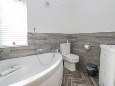 A bathroom with a bathtub a toilet a sink a window with blinds and a waste bin at Swifts Reach Lodge Kirkstone 10 Limefitt Park near Windermere