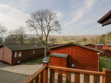 A view of wooden lodges with leafless trees and hills in the background at Swifts Reach Lodge Kirkstone 10 Limefitt Park near Windermere