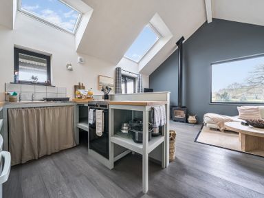A kitchen with windows, sink, stove, and a dining table at Grove Cottage in Kington