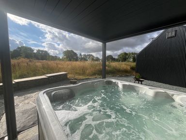 A hot tub next to a stone wall at Grove Cottage in Gladestry