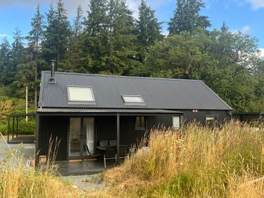 A black building with a deck and chairs at Grove Cottage in Gladestry