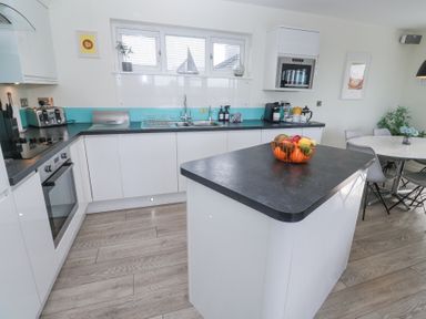 A kitchen with a black countertop island holding a fruit bowl and a dining area with chairs at Hepworth in Portreath