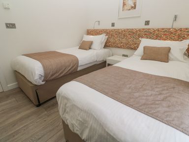 A bedroom with two single beds with beige throws and pillows and a patterned headboard at Hepworth in Portreath