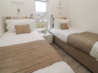 A bedroom with two single beds a nightstand with a flower vase and a window at Hepworth in Portreath