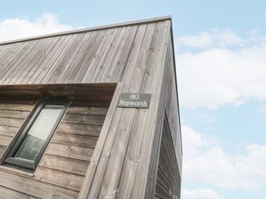 The exterior corner of a wooden building with a small window and a sign reading 80 Hepworth in Portreath
