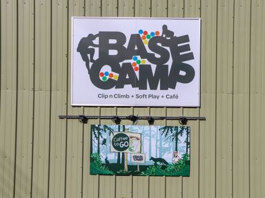 A building exterior with two signs one says BASE CAMP Clip n Climb Soft Play Cafe and the other advertises Coffee to Go