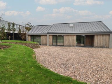 A modern house with gravel driveway and lawn at Harberton