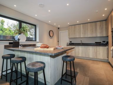 A kitchen with a counter and stools at Harberton in 