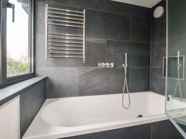 A bathroom featuring a bathtub, towel rail, and shower at Harberton