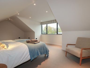 A bedroom with a bed and armchair at Harberton 