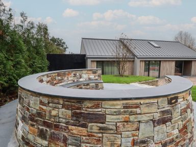 A stone wall and grass outside a modern house at Harberton