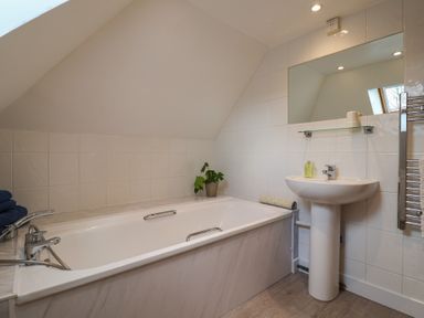 A bathroom with a bathtub sink mirror and towel rack at Garden Cottage in Upottery