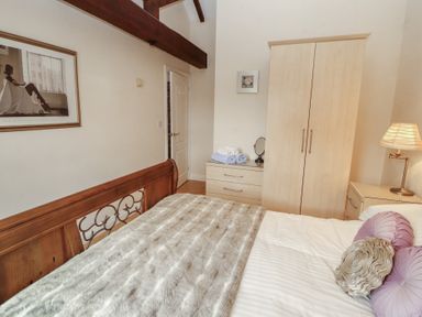 A bedroom with a bed and wardrobe at Millers Cottage in Seaville near Wigton