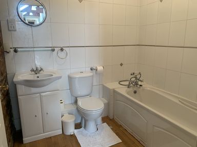 A bathroom with a bath tub, toilet, sink, and mirror at The Hayloft near Wigton