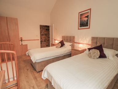 A bedroom with twin beds and a crib at The Hayloft near Wigton