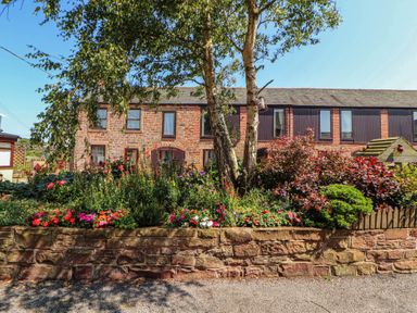 A garden with flowers and trees in front of a building at The Hayloft near Wigton
