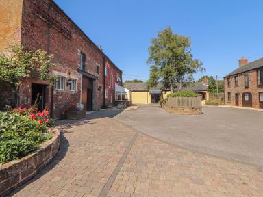 An outdoor area with brick buildings and flowers at The Hayloft near Wigton