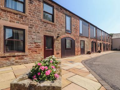 An outdoor area with a flowerbed and a building at The Coach House near Wigton