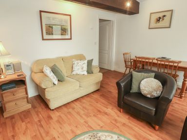 A living room with a sofa, lamp, and dining table at The Coach House near Wigton
