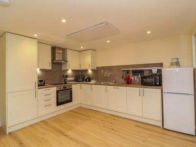 A kitchen with white cabinets a stainless steel oven a white fridge and wooden floor at Hideaway in Great Torrington
