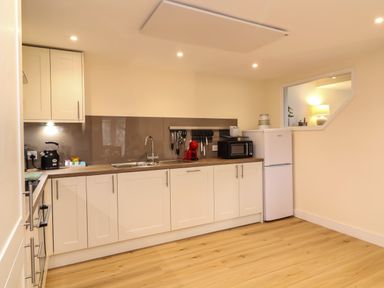 A kitchen with white cabinets wooden countertop appliances and a window at Hideaway in Great Torrington