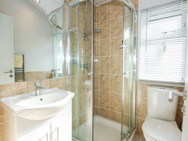 A bathroom with a corner shower enclosure sink with cabinet and a toilet at Ocean Breeze in Abersoch