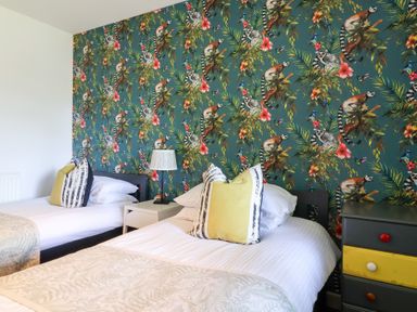 A bedroom with two beds and a floral wallpaper at Valley Lodge 37, St Ann's Chapel, Cornwall