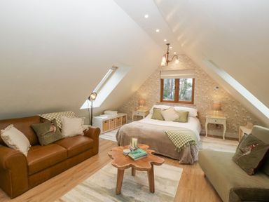 A bedroom with a bed two sofas a wooden coffee table and wallpaper with floral patterns at Pheasants Rise Apartment in Ross-On-Wye