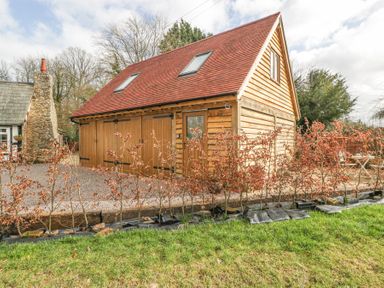 A wooden outbuilding with a red tiled roof and two skylights surrounded by small trees and grass at Pheasants Rise Apartment in Ross-On-Wye