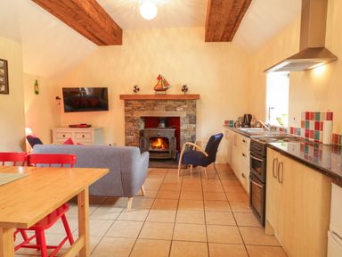 A living room with a fireplace and kitchen area at Shane's Cottage in Falcarragh, County Donegal