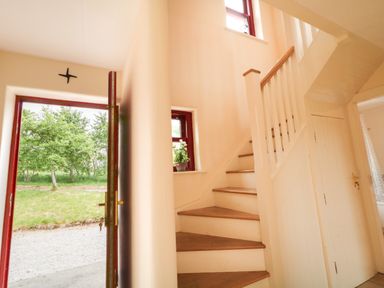 A hallway with a staircase and a front door at Shane's Cottage, Falcarragh, County Donegal
