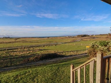 A grassy field with a wooden fence and steps leading down at Creag Mhor Lodge Back of Keppoch near Arisaig