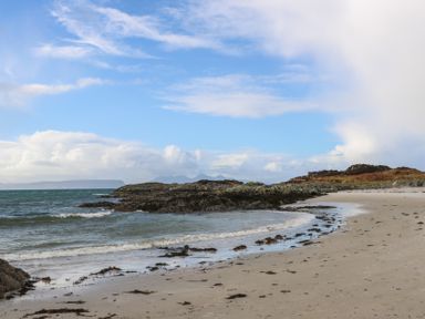 A sandy beach with seaweed and rocks by the ocean at Creag Mhor Lodge Back of Keppoch near Arisaig
