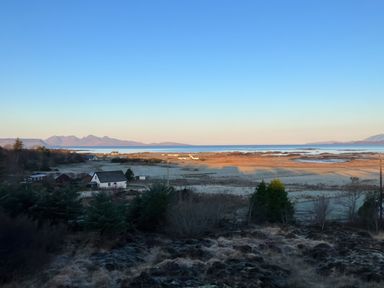 A coastal rural landscape with houses fields and mountains in the distance at Creag Mhor Lodge Back of Keppoch near Arisaig