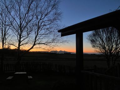 A sunset view with bare trees a picnic table and a fence at Creag Mhor Lodge Back of Keppoch near Arisaig