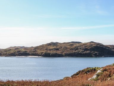 A body of water with hills and vegetation on the shore at Glen Mhor Lodge in Arisaig