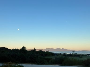 A landscape with trees hills a body of water and the moon at Glen Mhor Lodge in Arisaig