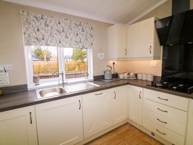 A kitchen with a sink under the window and cabinets and a stove at The Lake House in Marston near Barkston
