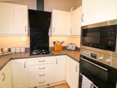 A kitchen corner with white cabinets a gas stove a toaster a microwave and an oven at The Lake House Marston near Barkston