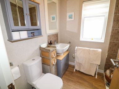 A bathroom with a toilet sink cabinet towel rack and window at The Lake House in Marston near Barkston