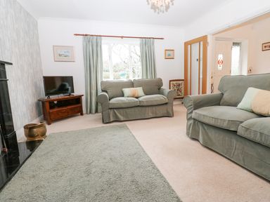 A living room with two sofas a television on a wooden stand and a window with curtains at Kerangarth in Corbridge