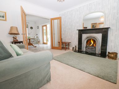A living room with a fireplace a green sofa and an open doorway leading to a dining area at Kerangarth in Corbridge