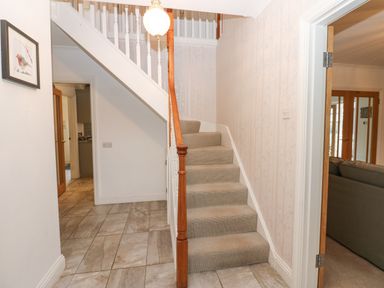 A hallway with tiled floor and carpeted stairs with wooden handrails at Kerangarth in Corbridge