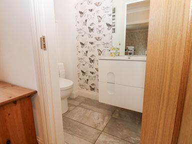 A small bathroom with a toilet and a sink with butterfly wallpaper at Kerangarth in Corbridge
