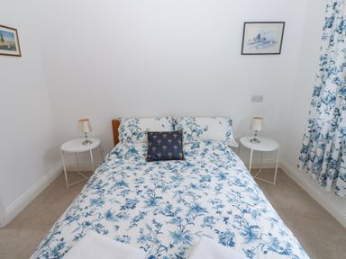 A bedroom with a bed with floral bedding two bedside tables with lamps and floral curtains at Kerangarth in Corbridge
