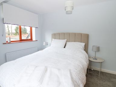 A bedroom with a bed with white linens bedside tables with lamps and a window with a blind at Kerangarth in Corbridge