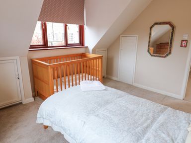 A bedroom with a wooden crib and a bed with a folded towel on it at Kerangarth in Corbridge